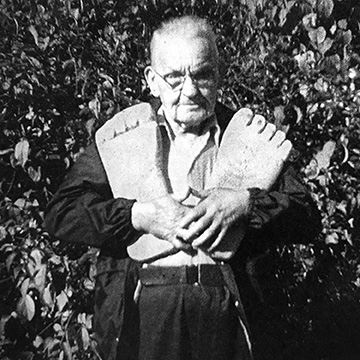 Rant Mullins holds two large wooden feet,